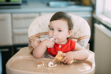 baby girl in the kitchen eating tubes with custard or protein cream