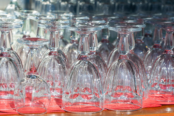 Many empty clean transparent wine glasses stand on a bar counter. Closeup