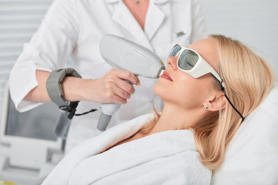 relaxed young blonde client receiving hair removal laser epilation. close up side view photo