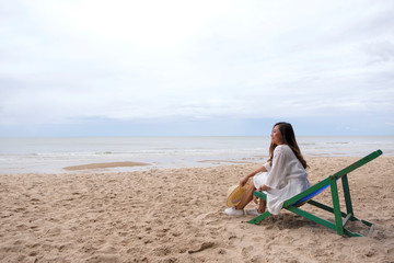 An asian woman sitting on a beach chair with feeling relaxed