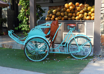 Blue empty vietnamese bicycle rickshaw on coconut background. Trishaw service is a popular public...