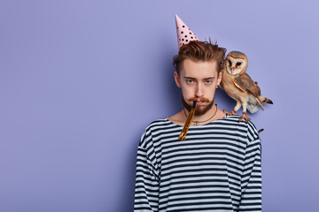 young man isn't satisfied with his birthday party, frustration concept. isolated blue background, studio shot,copy space