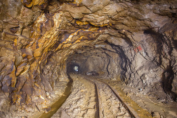 Obraz premium Gold ore mine shaft tunnel underground with rails