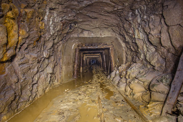 Gold ore mine shaft tunnel underground with rails