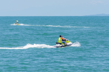 Sports activities on the Black sea. A Muslim woman rides a water scooter with an instructor on a Sunny summer day. A photo from the back.