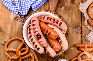 Traditional German sausages and pastry brezel for a beer festival. Wood background and decor. View from above. Banner