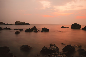 Still water and rocks during sunset on a beach