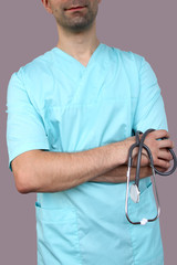 male doctor in blue uniform with professional clothes with a stethoscope in hands, medical concept, close-up, copy space
