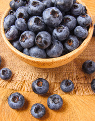Raw fresh huckleberry in a bowl. Wooden background.