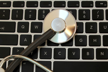 medical stethoscope on a black laptop keyboard, copy space, close-up