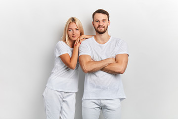Young happy cheerful couple in white t-shirts posing to the camera on white background.fashion, beauty, people concept
