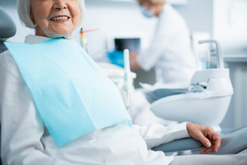 Happy mature woman is sitting in dental chair