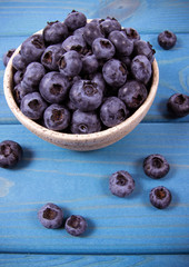 Raw fresh huckleberry in a bowl. Wooden background.