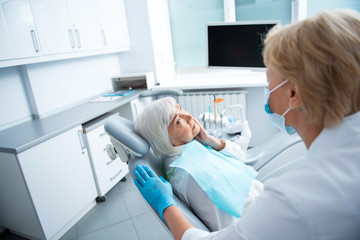 Obraz premium Adult lady sitting in dental chair during professional teeth cleaning