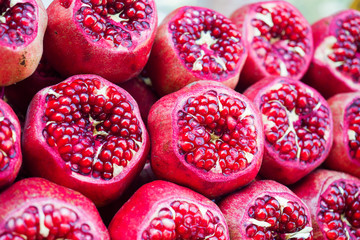 Background of fresh ripe pomegranates with incision on the counter in the street market.