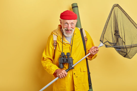 man is crazy about fishing . positive feeling and emotion. necessary equipment. professional fishman with binocular and equipment going to river. close up photo. isolated yellow background