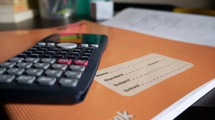 A calculator and a book on a table.