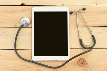 Stethoscope and tablet on wooden background. The concept of technology and medicine, distant treatment, health. Top view image. Copy space for text.