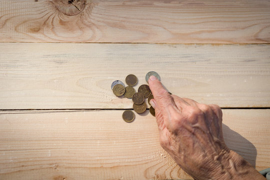 Hands of an elderly man holding coins. The concept of lack of money, the poor, the small pension of old people. Image.