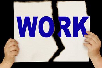 female hands are holding on a black background a sheet of cardboard torn in two with the word work, concept of dismissal, conflict