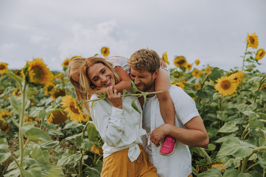 Young family laughing together in sunflower field in summer