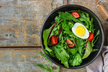 healthy salad with boiled egg, mix lettuce leaves, tomatoo, appetizer, snack. food background. top view. copy space