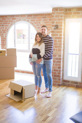 Young beautiful couple hugging at new home around cardboard boxes