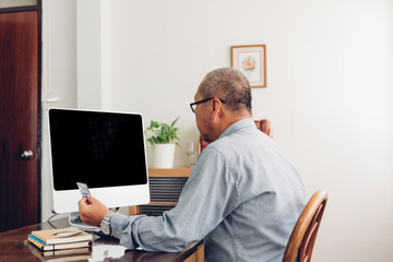 Senior man shopping online using computer and credit card.