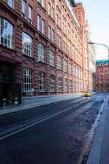 historic street with red brick houses and yellow taxi on wet asphalt in Moscow Russia