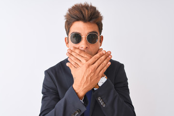 Young handsome businessman wearing suit and sunglasses over isolated white background shocked covering mouth with hands for mistake. Secret concept.