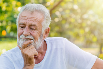 Senior Caucasian man with thoughtful expression outdoors.