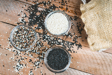 Fototapeta na wymiar Different types of sesame seeds. White, black and multi-colored sesame seeds. Seasonings on a wooden background.