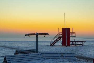 Empty beach in the Baltic in winter. Frozen sea covered with snow at sunset.