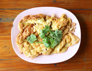 Top view of Omelet with green coriander on wood table.
