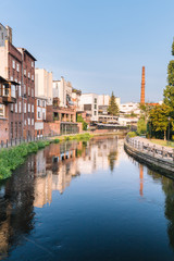 Fototapeta na wymiar Bydgoszcz in Poland. Picturesque channels of the Brda River flowing through the city center. Old historic factory and residential buildings stand along the river
