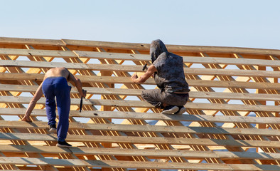 Workers are building the roof of the house from wood