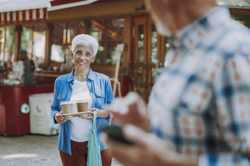 Smiling woman carrying coffee and looking at husband stock photo