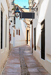Street with white houses and narrow in Cordoba, Spain in a sunny day