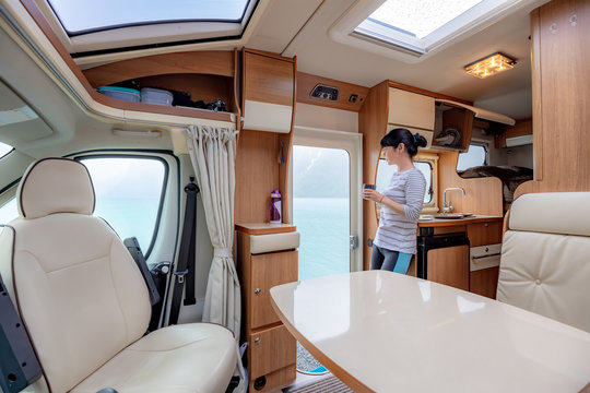 Woman in the interior of a camper RV motorhome with a cup of coffee looking at nature.