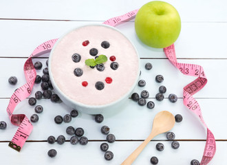 Yogurt with fresh of berries in blow ,green apple and measuring on wooden background,die lifestyle t concept