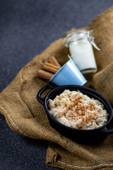 Cinnamon rice pudding in cast iron pot, with a milk bottle and cinnamon sticks