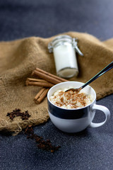 Cinnamon rice pudding in a cup, with a milk bottle and cinnamon sticks