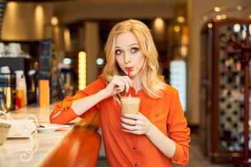Young girl drinking coffee from tube sitting bar