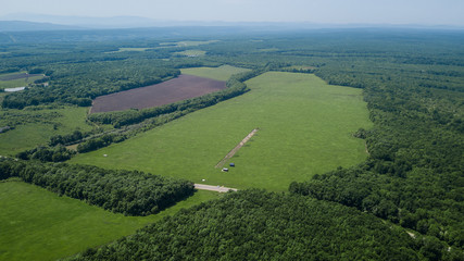 Fototapeta na wymiar Aerial landscape nature - Dense green forest, green meadows, blue sky in southern Russia