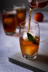 Peach iced tea being poured into a glass