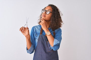 Young brazilian hairdresser woman using scissors standing over isolated white background serious face thinking about question, very confused idea