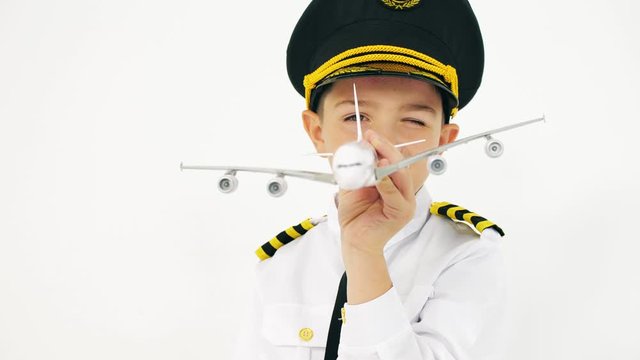 Boy wearing pilot's uniform plays with toy airliner