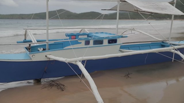 Philippines fish boat stands on the sandy beach of Palawan island near El Nido