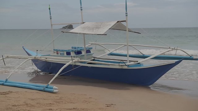 Philippines fish boat stands on the sandy beach of Palawan island