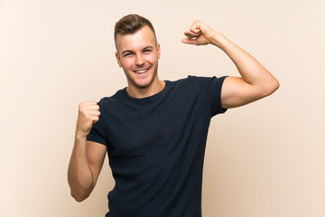 Fototapeta premium Young handsome blonde man over isolated background celebrating a victory